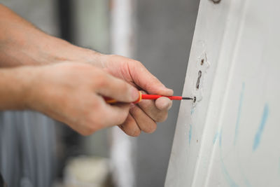 A young man unscrews a bolt from an old door with a screwdriver.