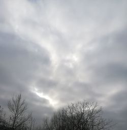 Low angle view of bare tree against cloudy sky