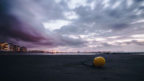 Sea by cityscape against sky during sunset