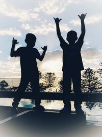 Silhouette people photographing against sky