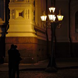 Man standing by illuminated lamp at night