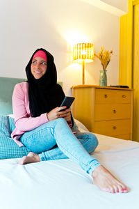 Young woman using phone while sitting at home