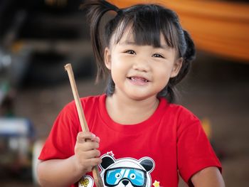 Portrait of cute smiling girl holding wooden stick