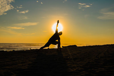 Silhouette man on beach against sky during sunset