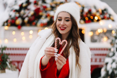 A beautiful young woman with red lips in a hat stands by a decorated christmas van on the street