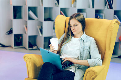 Young woman sitting on chair at home