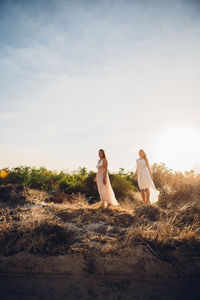 Young women standing against sky