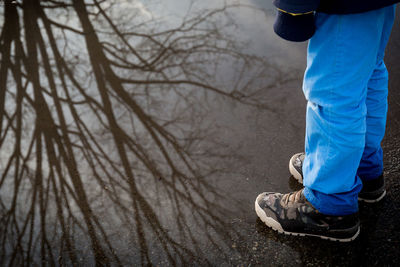 Low section of man with reflection standing on road