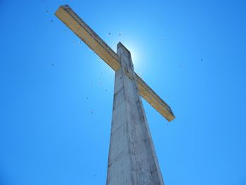 Low angle view of cross on wood against clear blue sky