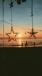 Silhouette people on beach against sky during sunset