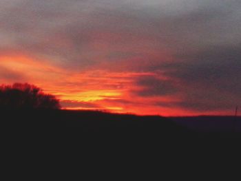 Silhouette landscape against orange sky