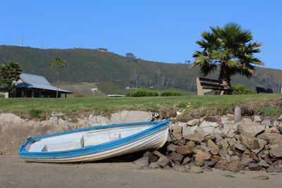 Boats moored on beach by houses against sky