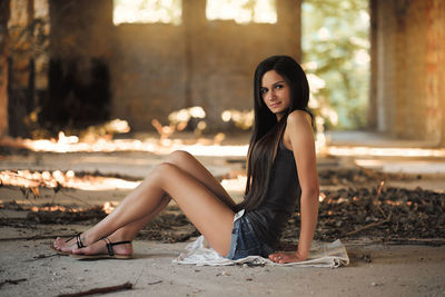 Portrait of young woman sitting in abandoned building