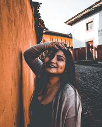 Portrait of smiling young woman standing against building