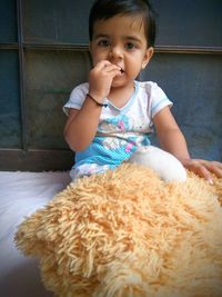 Portrait of cute girl playing with teddy bear at home