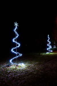 Illuminated christmas tree on field at night