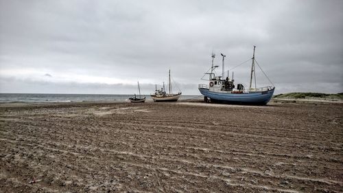 Boats moored on beach against sky