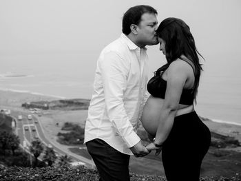 Rear view of couple kissing against clear sky