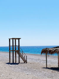 Lifeguard hut on beach against clear blue sky