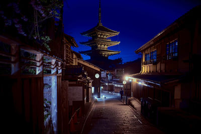 Illuminated alley amidst buildings against sky at night