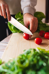 Cropped hands of man cutting vegetables on table