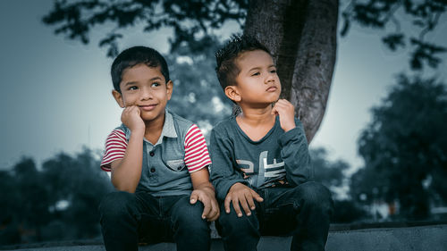 Happy friends sitting against trees