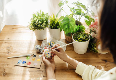 Female painted handmade easter eggs painted. brushes and paints with flowers and plants. 