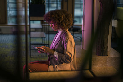 Businesswoman using tablet computer in illuminated office