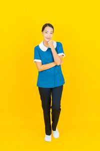 Portrait of smiling young woman against yellow background