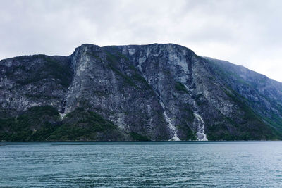 Rock formation by sea against sky