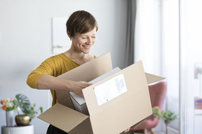 Smiling woman unpacking parcel at home