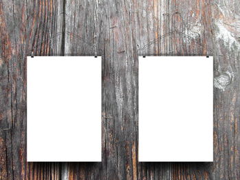 Low angle view of blank papers hanging on wooden wall