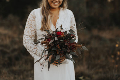 Young woman holding white flower standing on field