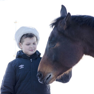 Boy standing with horse against clear sky