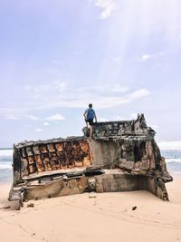 Rear view man standing of broken ship at shore