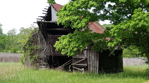 Low angle view of abandoned house on field