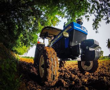 Low angle view of tractor on field against trees