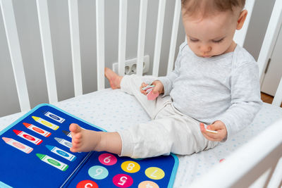 High angle view of cute baby girl sitting on bed at home