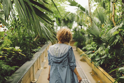 Rear view of young woman standing on footpath