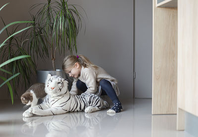 A little girl sits on the floor and holds a cat in her hands