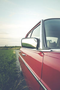 Close-up of vintage car on field against sky