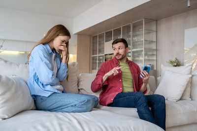 Family in argument on sofa, woman cries and suspects husband of unfaithfulness. marital discord