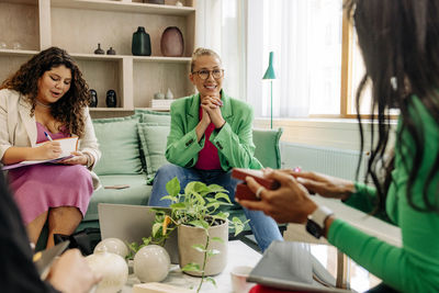 Smiling female boss listening to female colleague during meeting at office