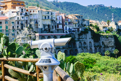 Close-up of coin-operated binoculars against buildings in coastal town in italy