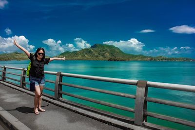 Full length portrait of young woman standing against sea