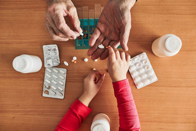 Grandchild helping grandfather to organize medication into pill dispenser. senior man routine