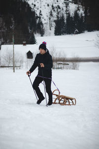 Hiker pulls to the top of a wooden sled for a ride on the piste. portrait of a man pulling a sledge.