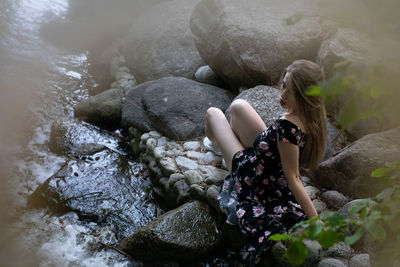 Woman sitting on rock by water