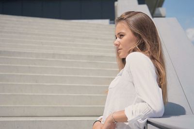 Side view of young woman sitting on staircase