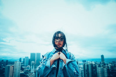 Woman with umbrella in city against sky